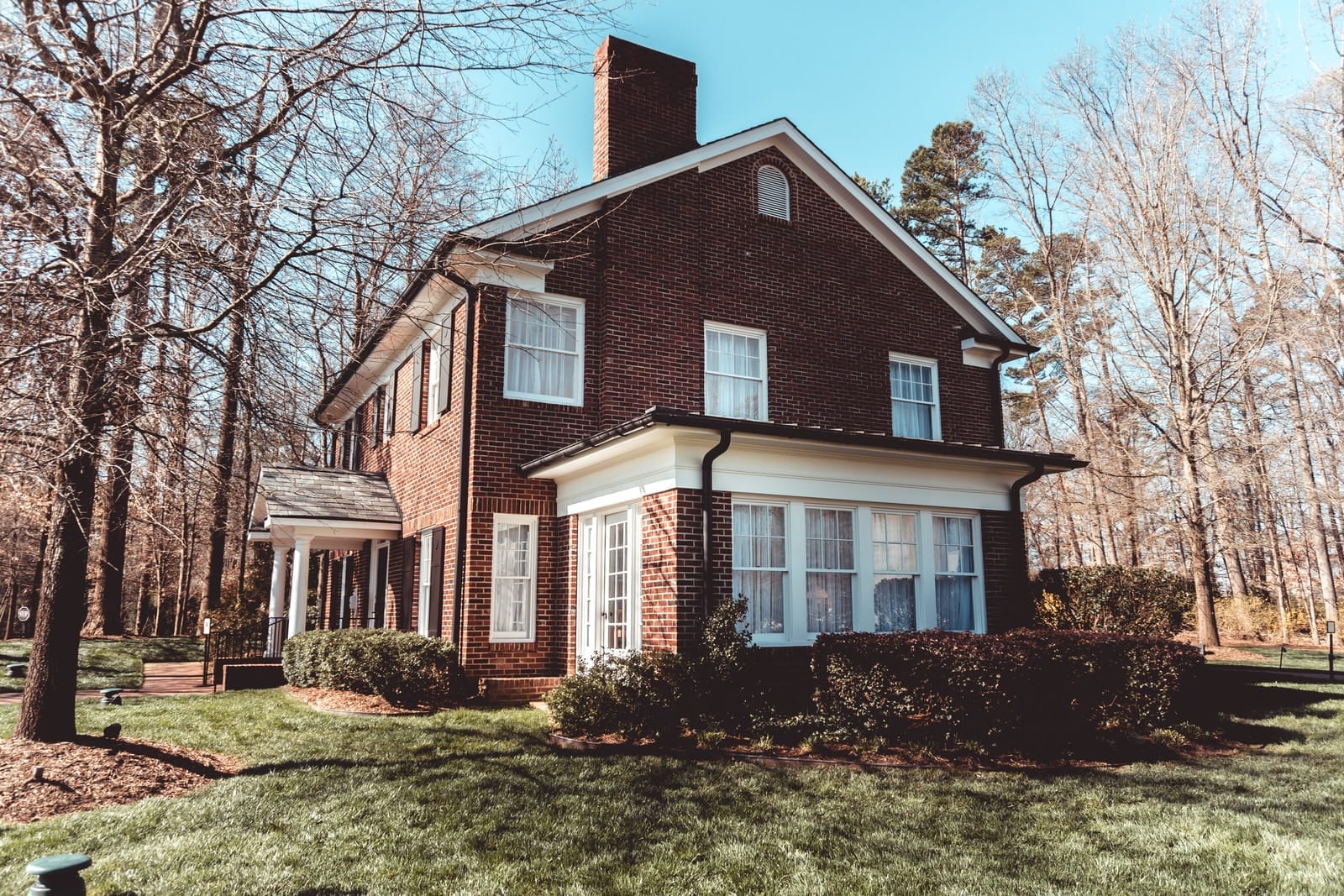 brown and white concrete house near bare trees under blue sky during daytime
